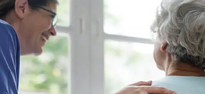 Anciana recibiendo abrazo de asistente